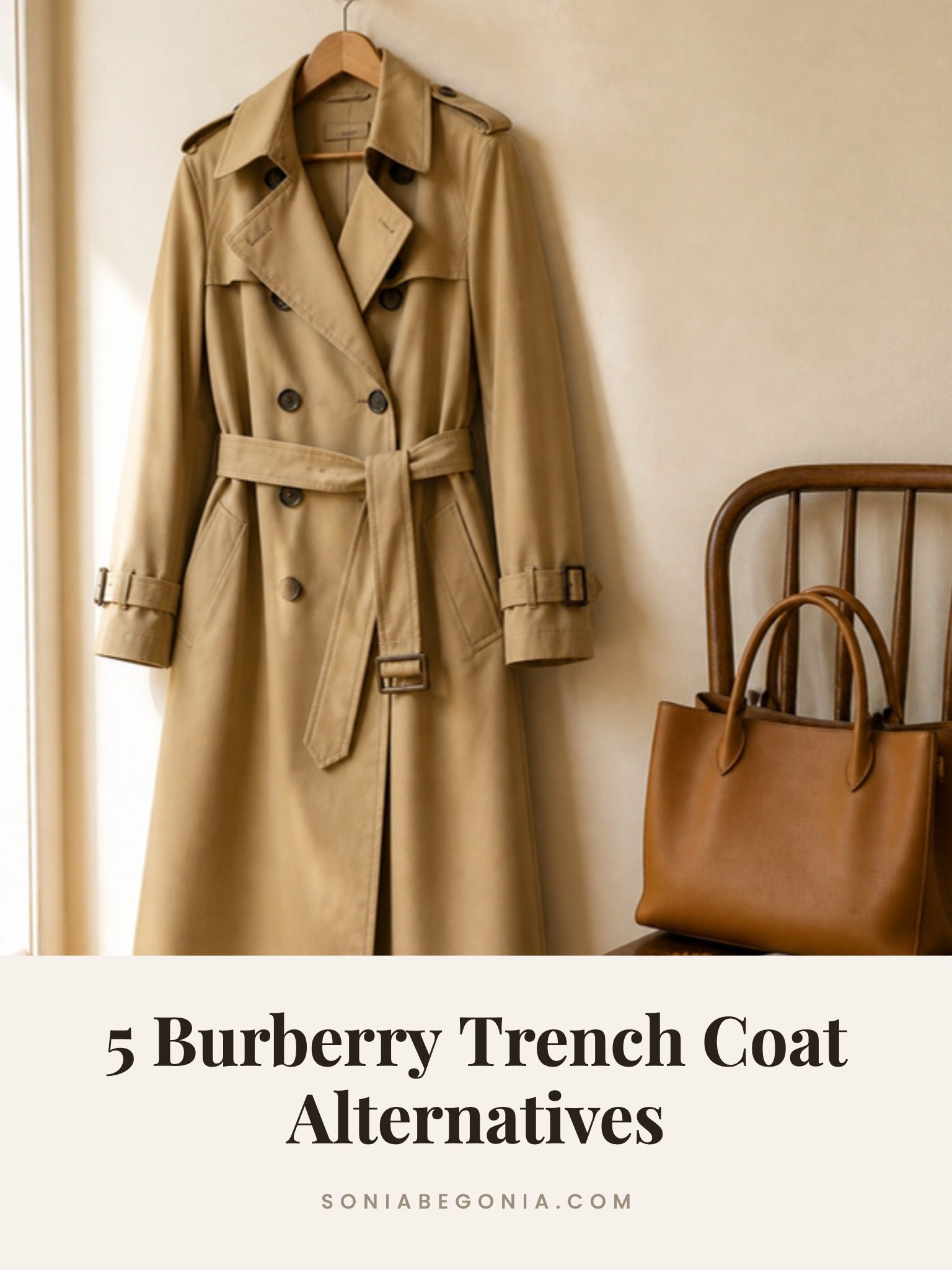 Burberry trench coat alternatives: a khaki belted trench coat hanging on a cream wall next to a tan tote