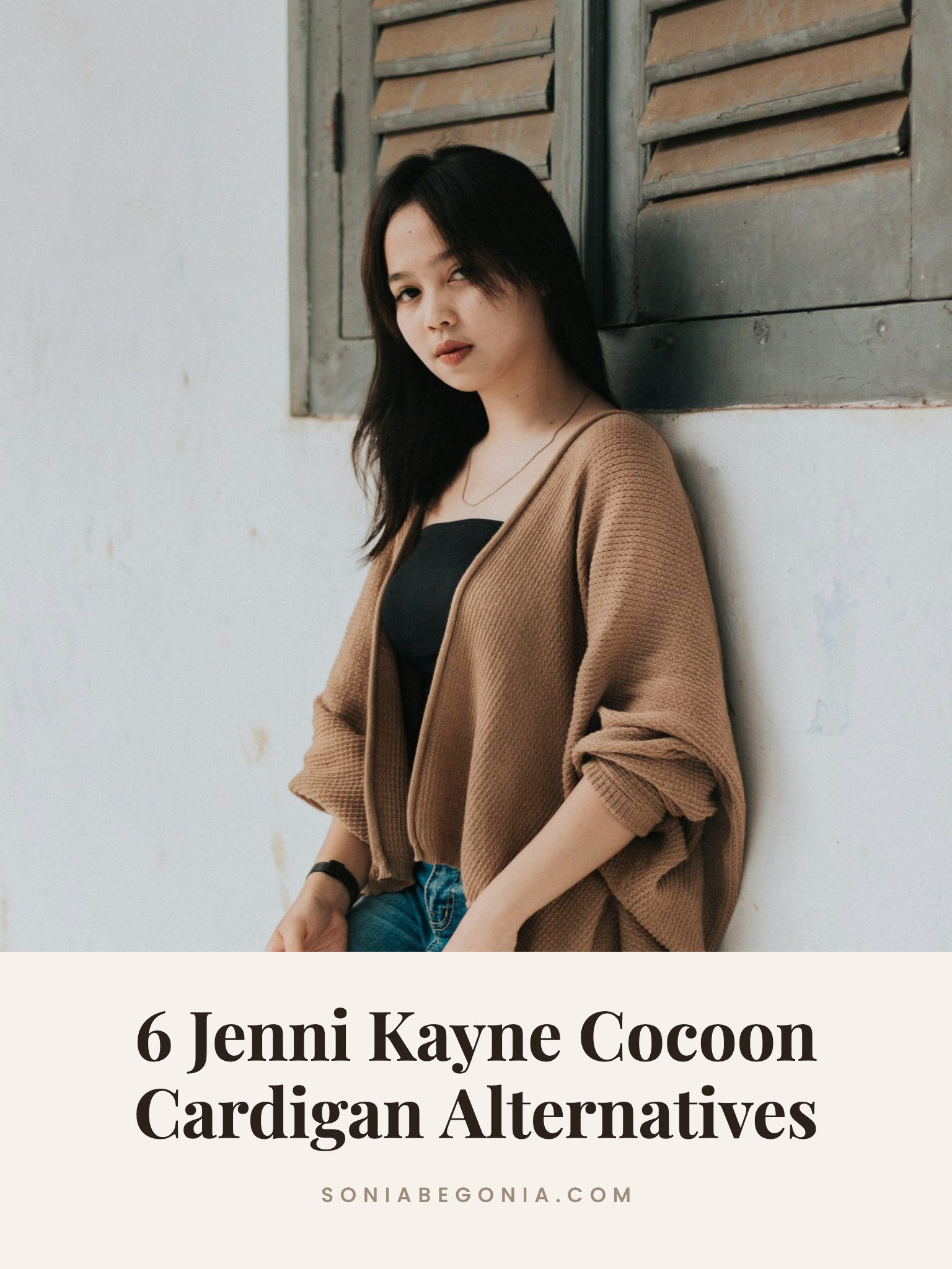 Jenni Kayne cocoon cardigan alternatives: camel oversized cocoon cardigan styled with a black top and jeans against a white wall