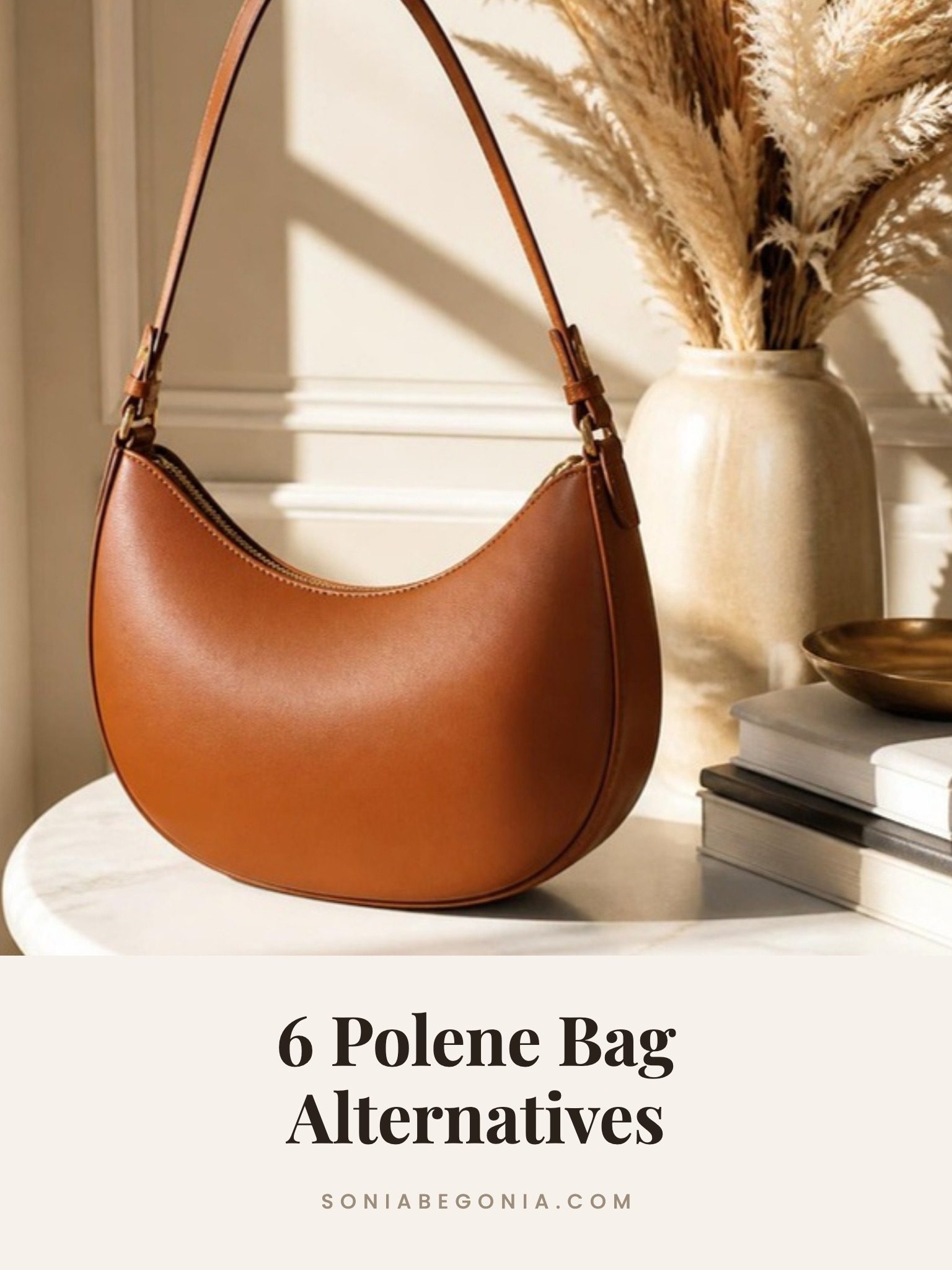 Polene bag alternatives: a caramel leather half moon shoulder bag on a white marble table